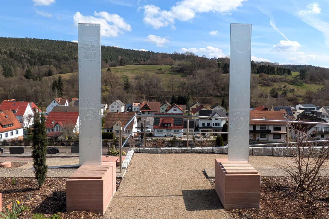 Zwei Glasstelen im Hintergrund der Ort Frammersbach